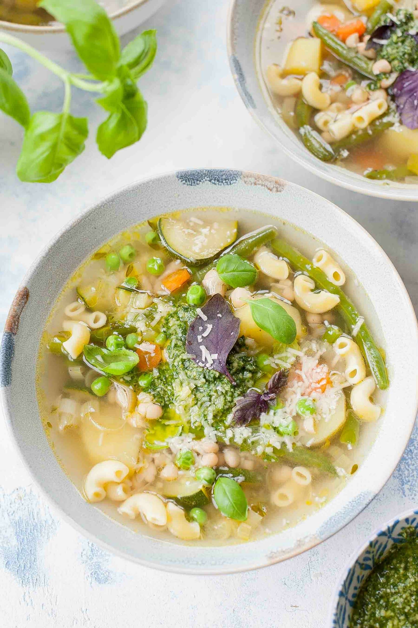 Soupe au pistou in a blue bowl garnished with basil leaves.