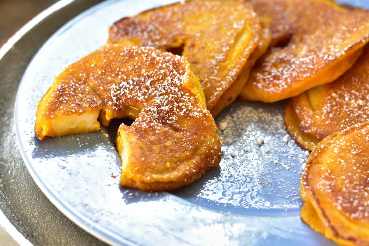 Slose up photo of apple ring pancakes on a blue plate.