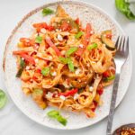 Tagliatelle pasta with zucchini, bell pepper and feta on a white plate.