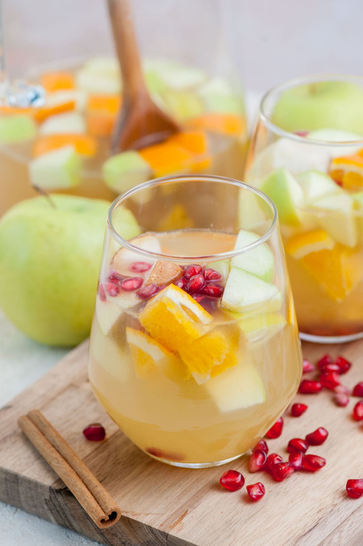 Two glasses with apple cider sangria on a wooden board.